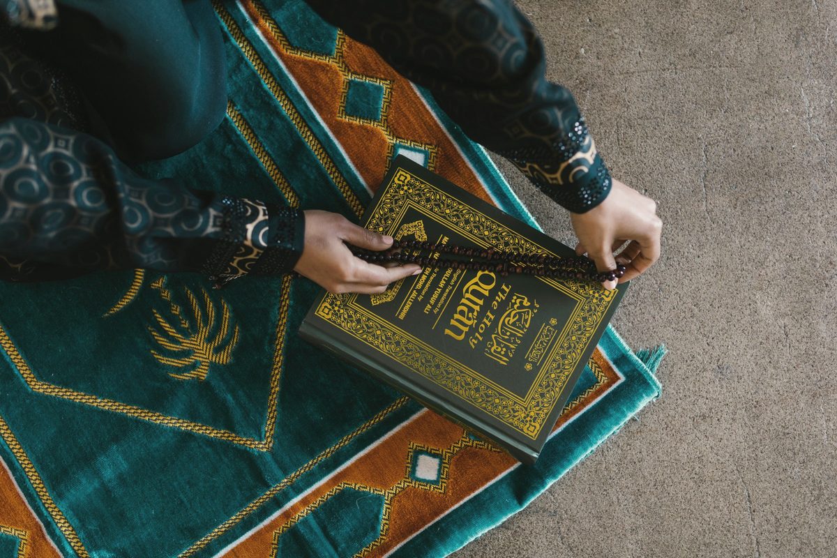 Hands holding prayer beads over a book