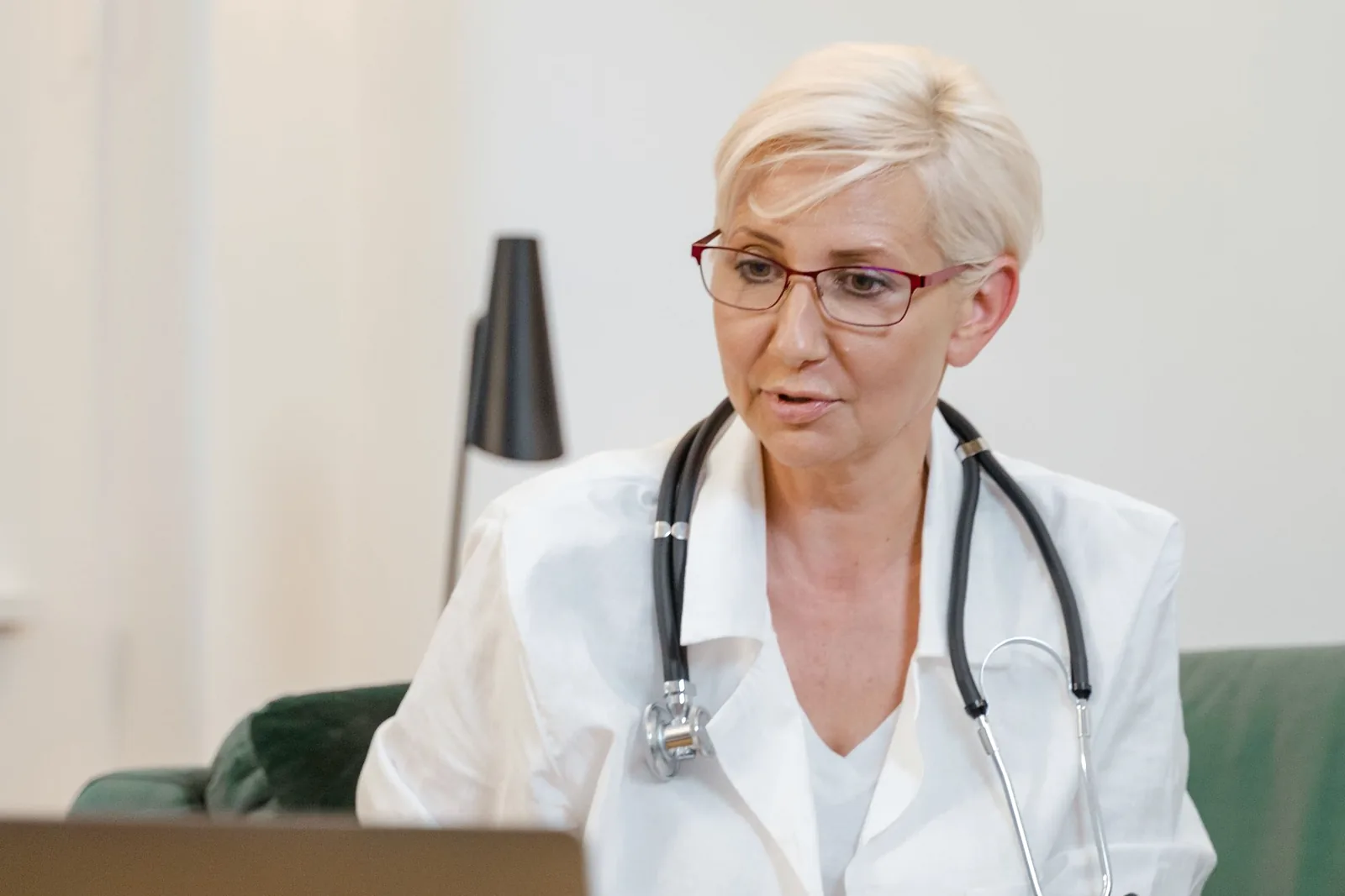 Doctor in a white coat on a video call at a laptop