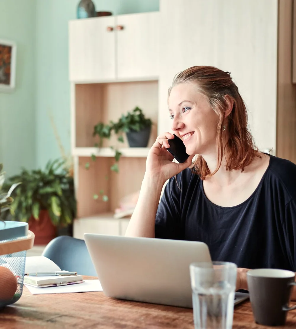 Woman smiling on a telehealth phone call at her desk at home