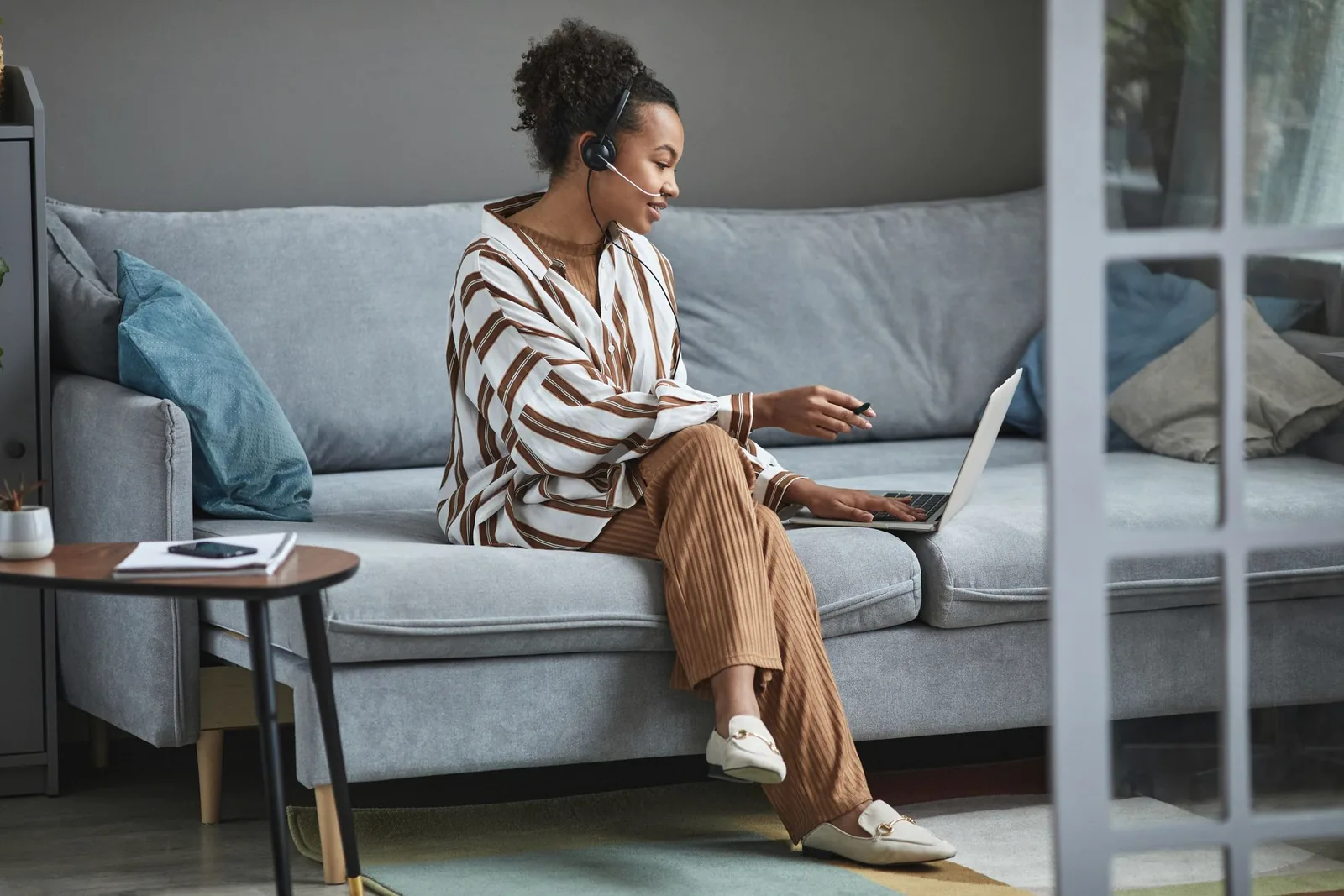 Woman on a video consult on her laptop from her sofa at home