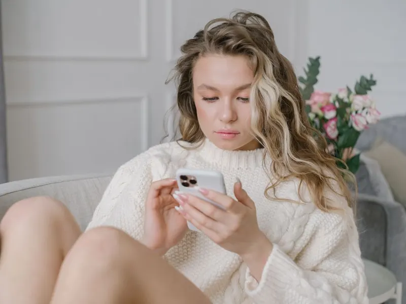 Woman filling in a form on her phone on the sofa