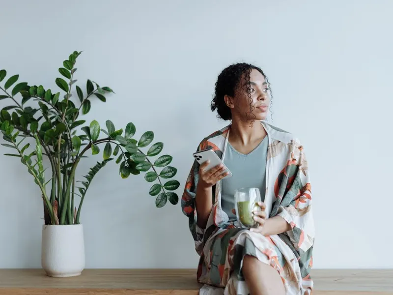 Relaxed woman at home beside an indoor plant