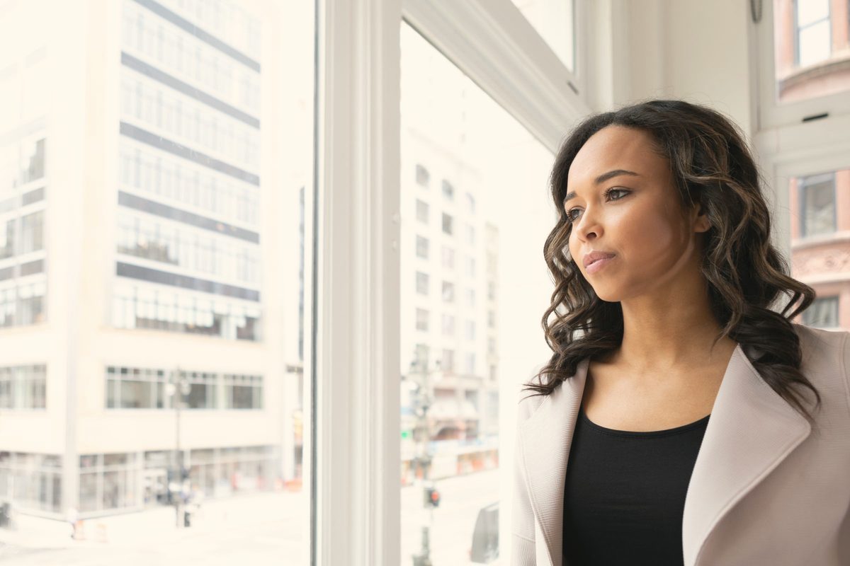 Hopeful woman gazing out of a bright window
