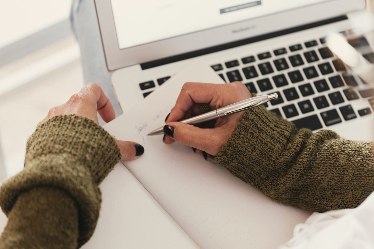 Woman taking notes beside her laptop