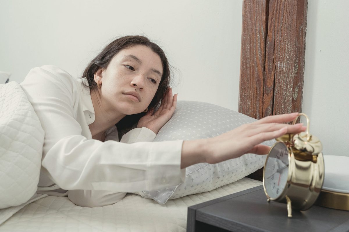 Young woman waking up with alarm clock