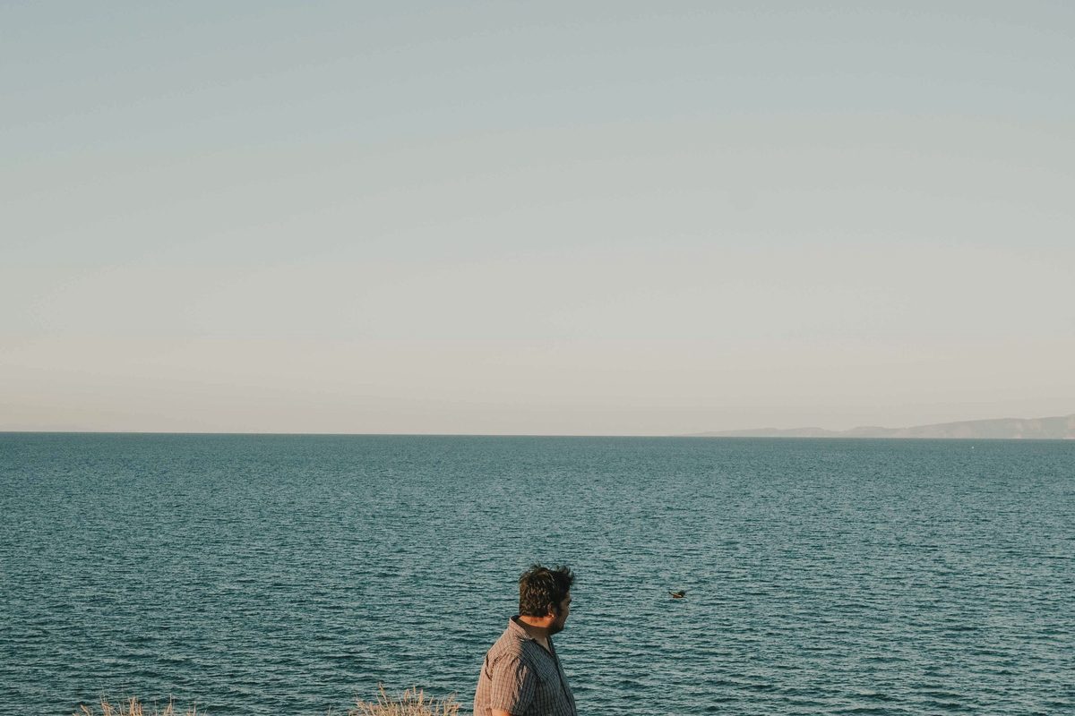 Man standing on coastal cliff overlooking ocean view