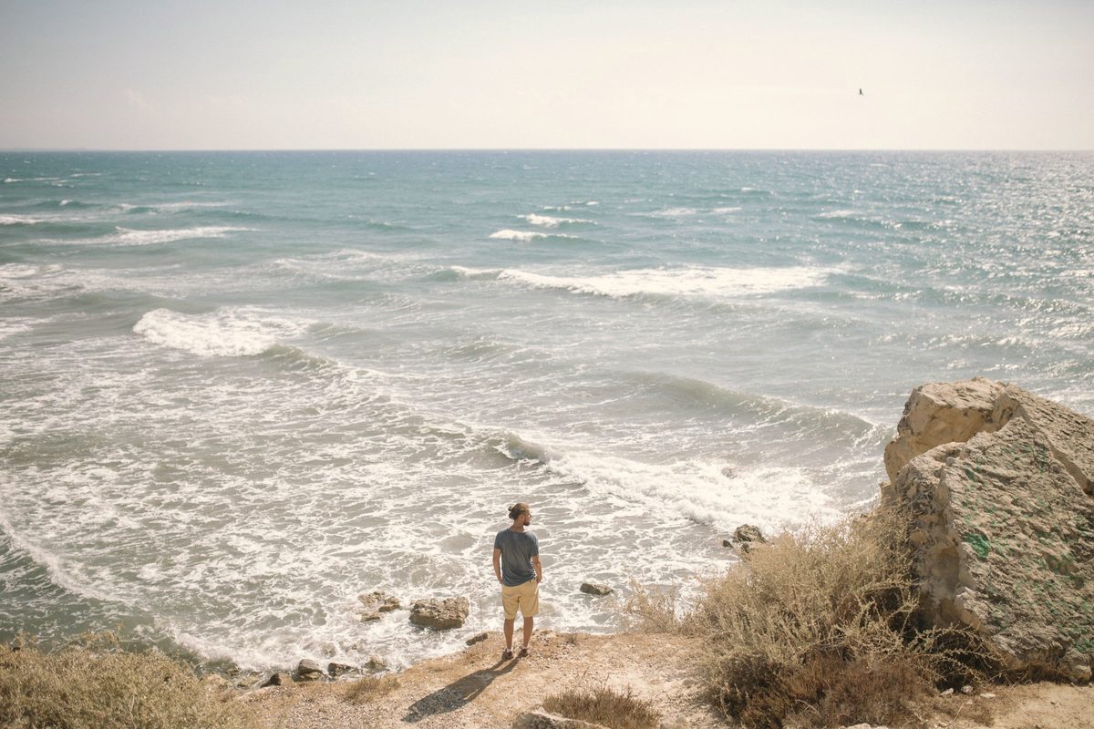 A man standing on a cliff looking sideways