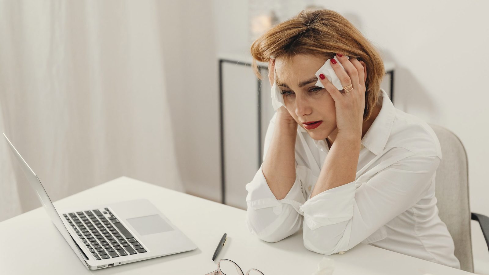 Stressed woman holding her head at her laptop