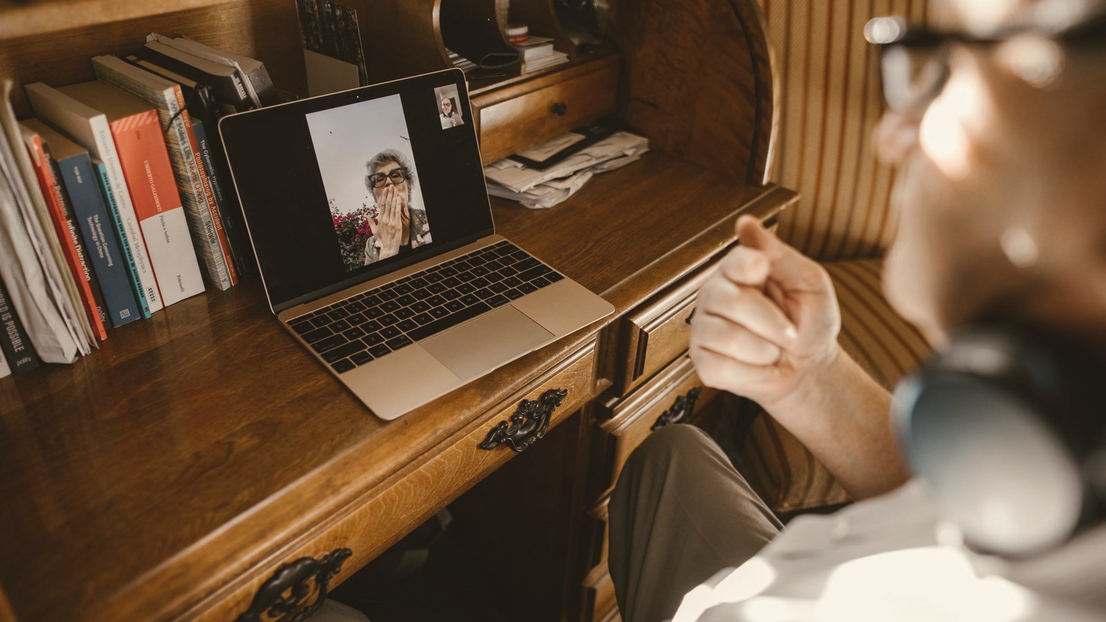 Person on a video call using a laptop at a wooden home desk
