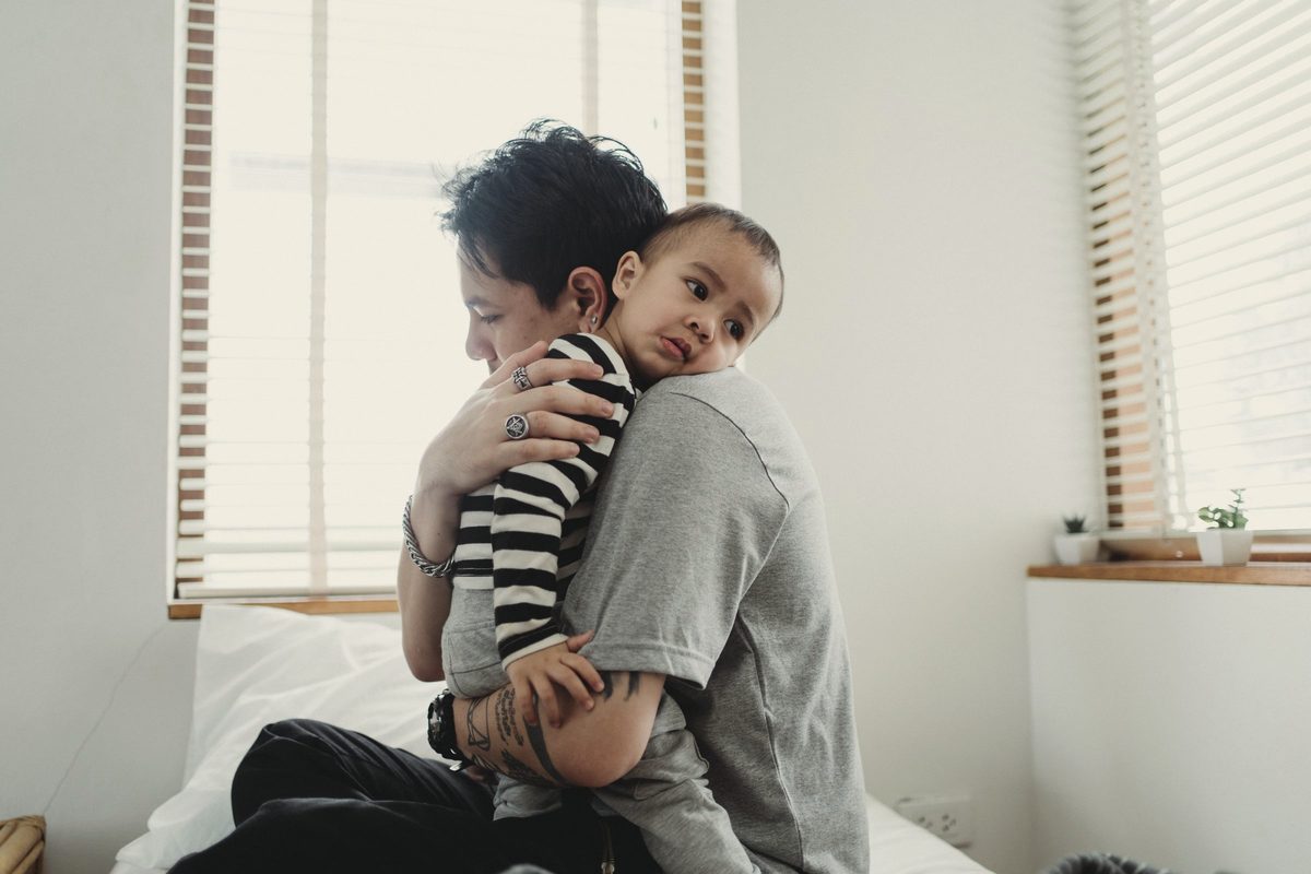 Mother hugging child on bed