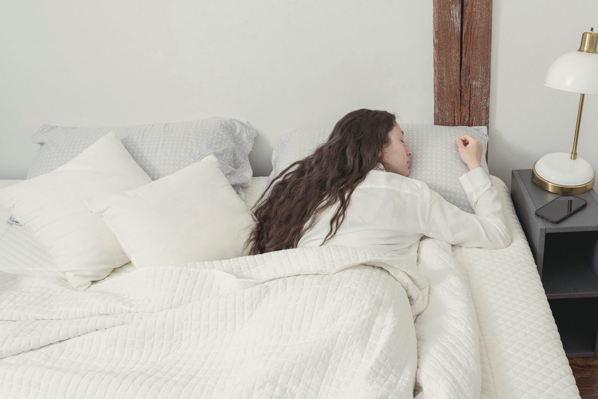 Woman sleeping peacefully in a white bed