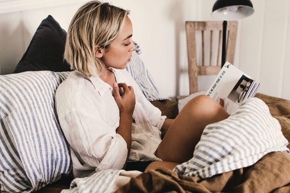 Young woman reading book in bed