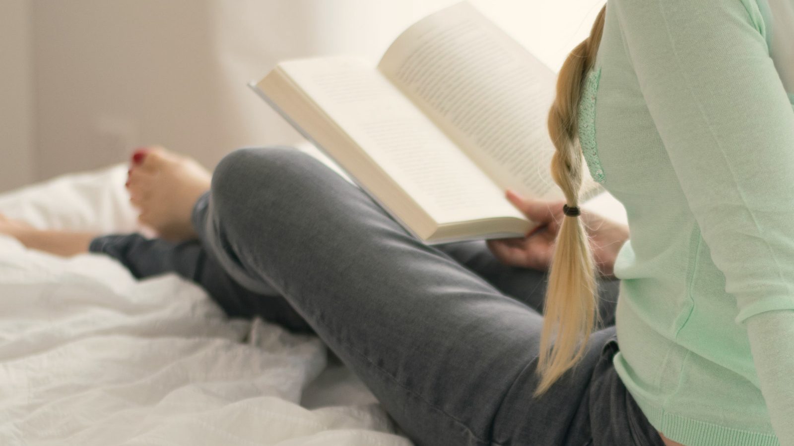Person reading a book in bed