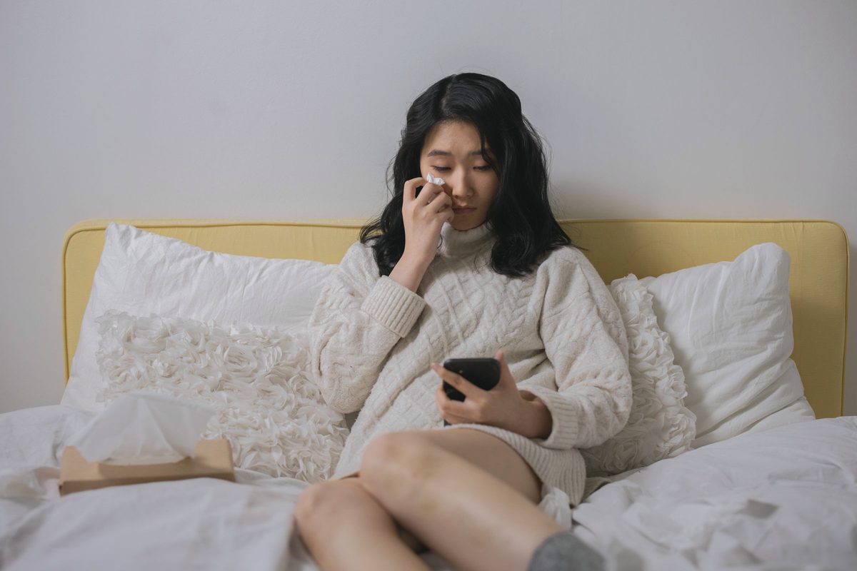 Woman sitting up in bed looking at her phone
