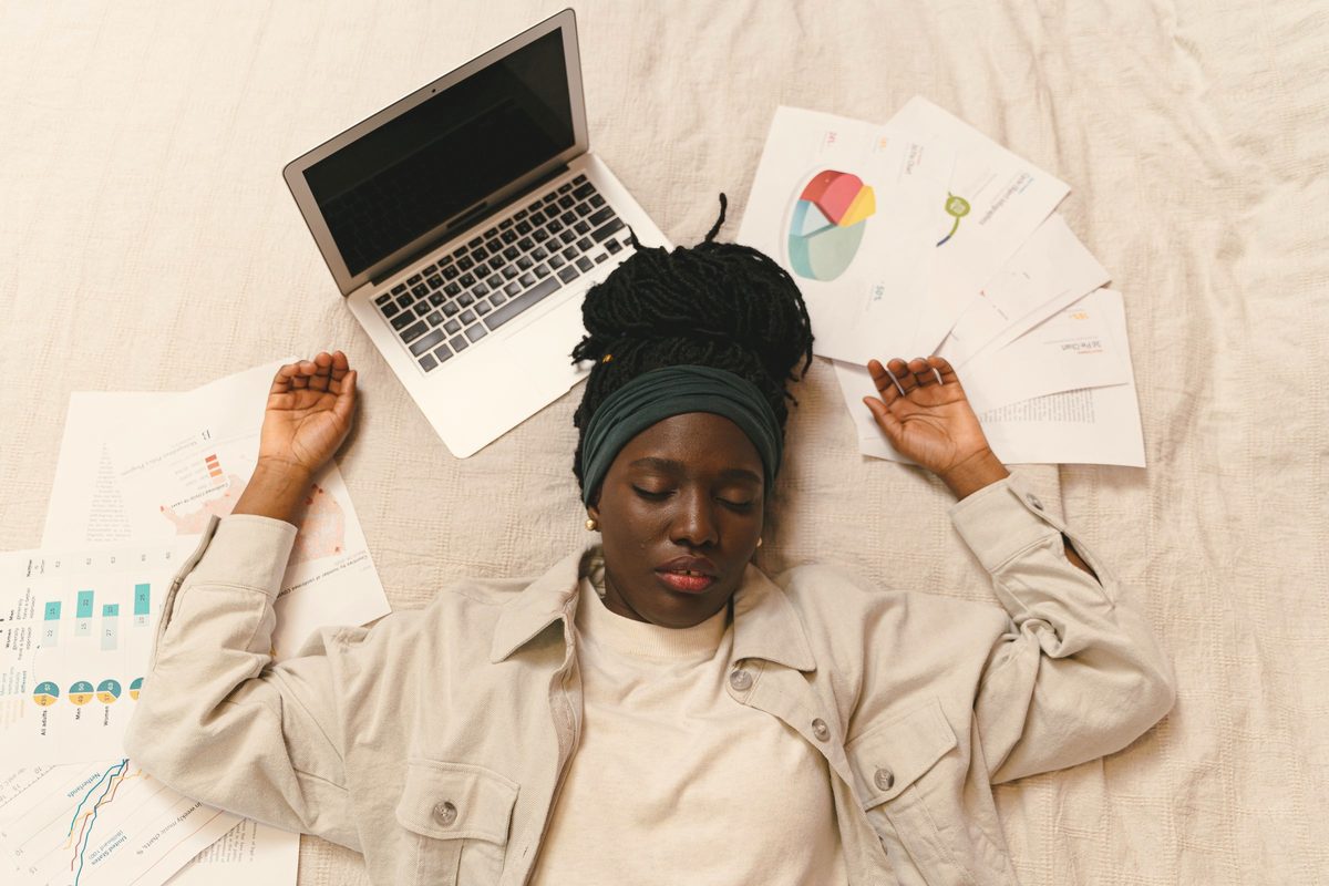 Tired woman lying on the floor beside her laptop and papers
