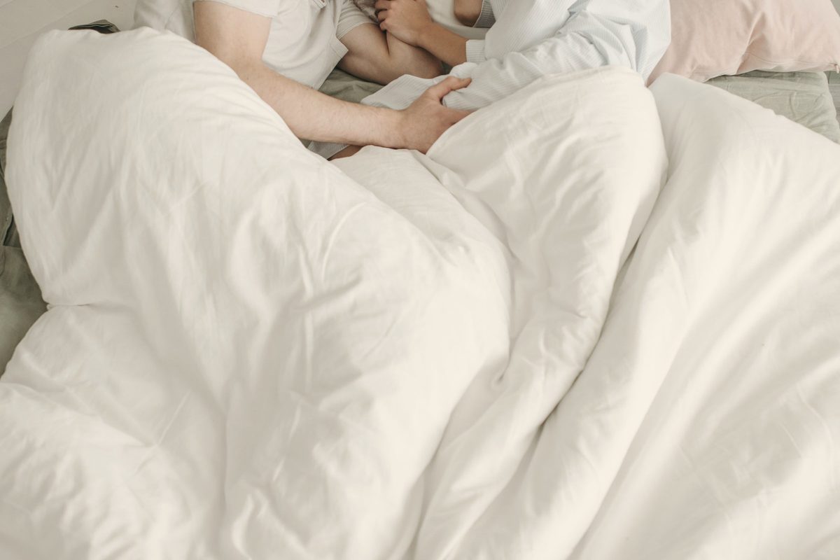 Couple sleeping under a white duvet