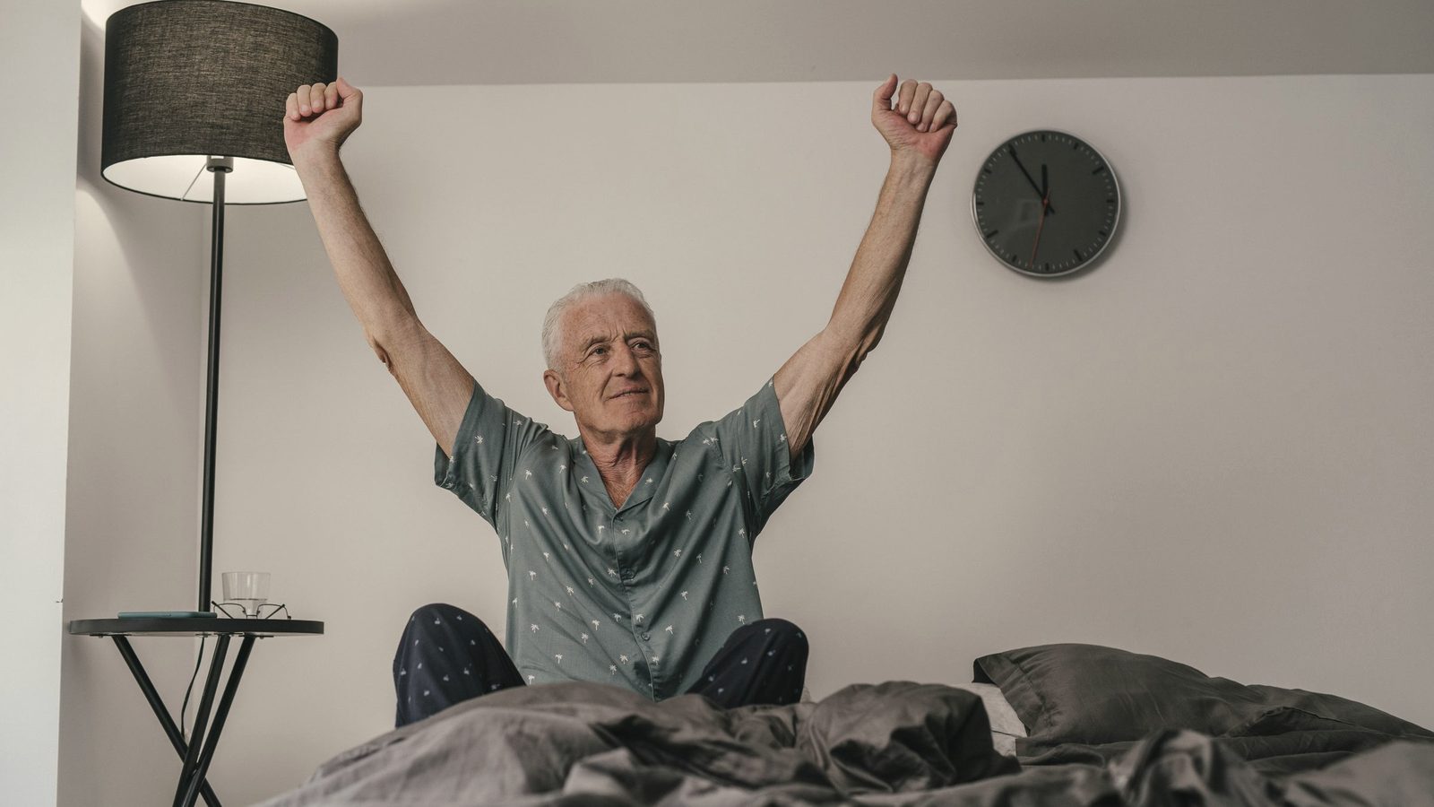 Older man stretching his arms as he wakes up