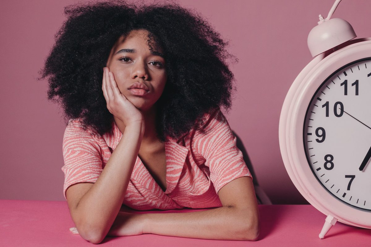 Woman looking tired beside a big alarm clock