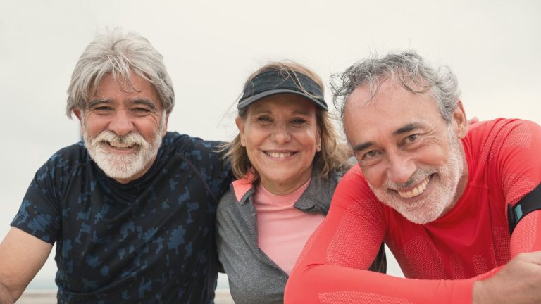 Three older friends smiling together outdoors after a walk