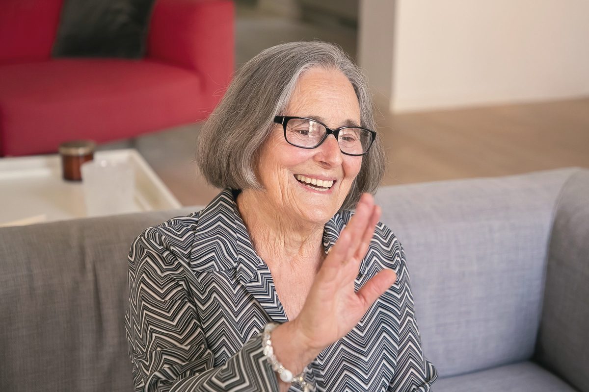 An older woman smiling on a sofa