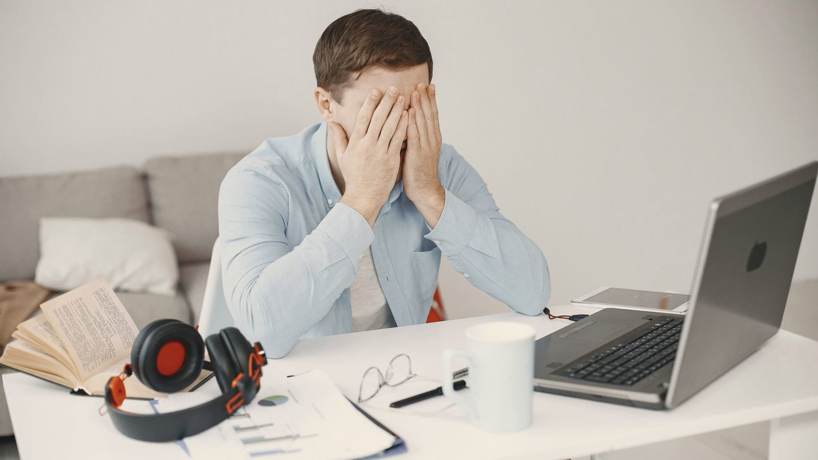 Frustrated man covering his face at his home office desk