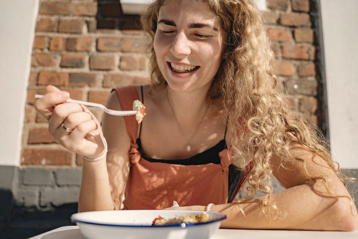 Smiling woman eating lunch at a sunny table