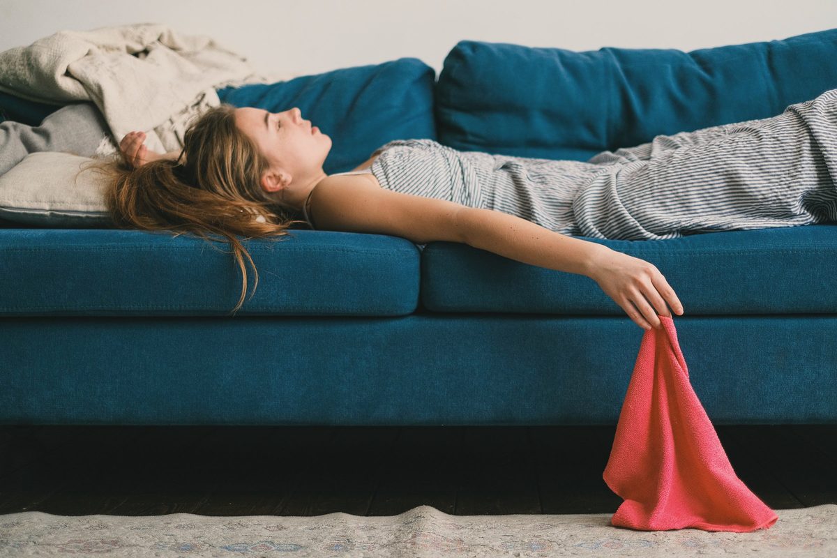 Exhausted woman lying back on a blue sofa