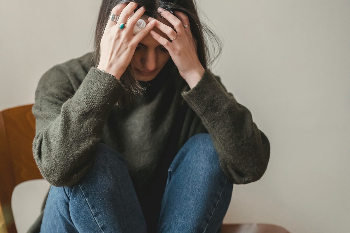 Stressed young woman grabbing head while sitting on chair