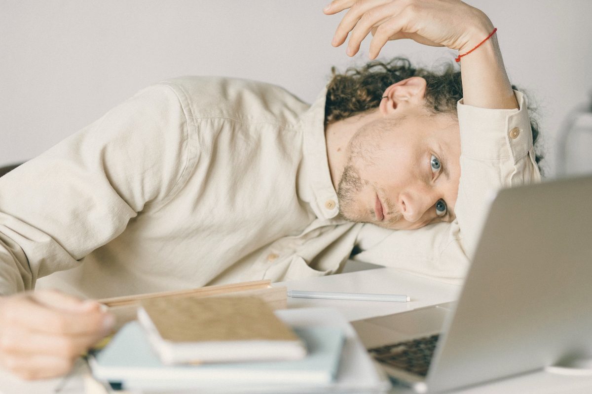 Overworked man resting his head beside his laptop