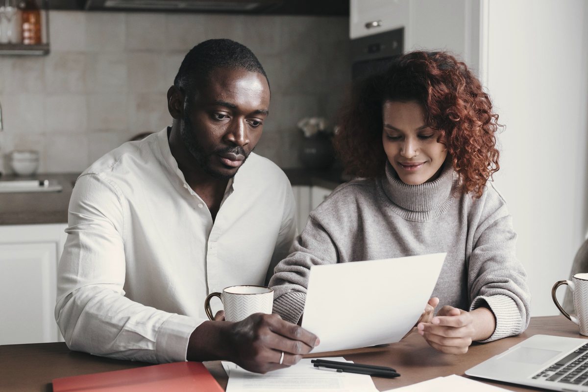 Couple at a kitchen table reading through paperwork together before changing clinics