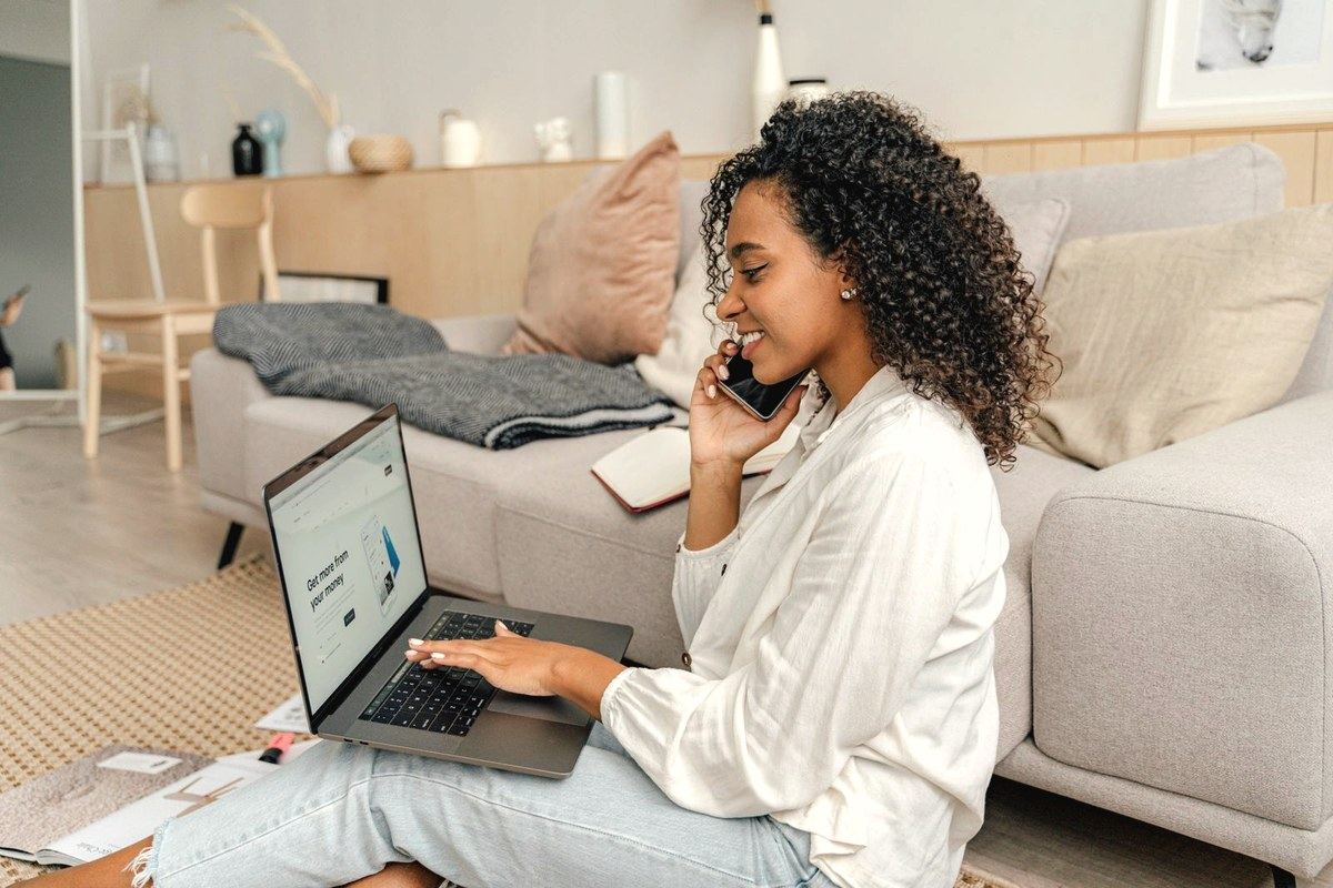 Person booking a telehealth consult appointment by phone with a laptop at home