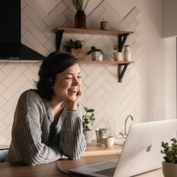 Woman smiling on a telehealth consult at her laptop in a bright kitchen