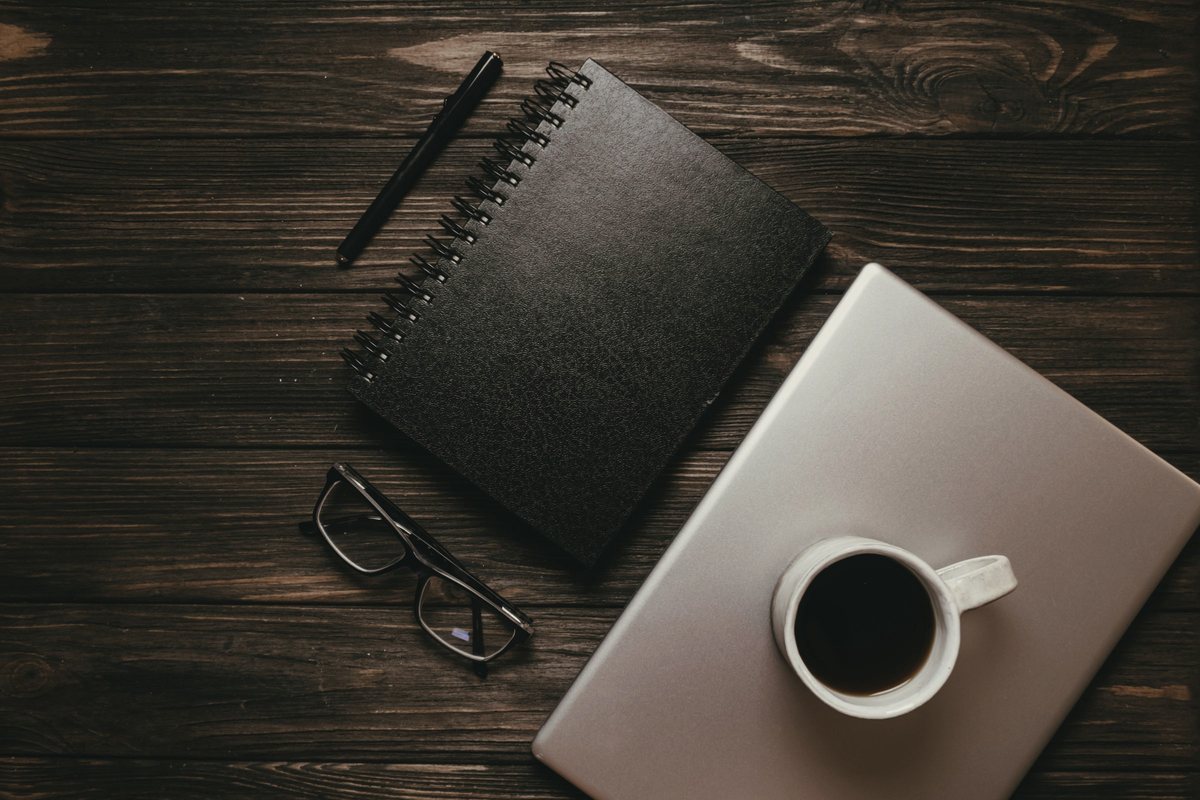 Notebook, pen, glasses and coffee on a desk, ready to note what you need for telehealth with no referral