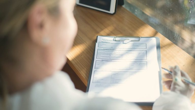 Woman at a sunlit desk filling in details to book a telehealth consult with no referral