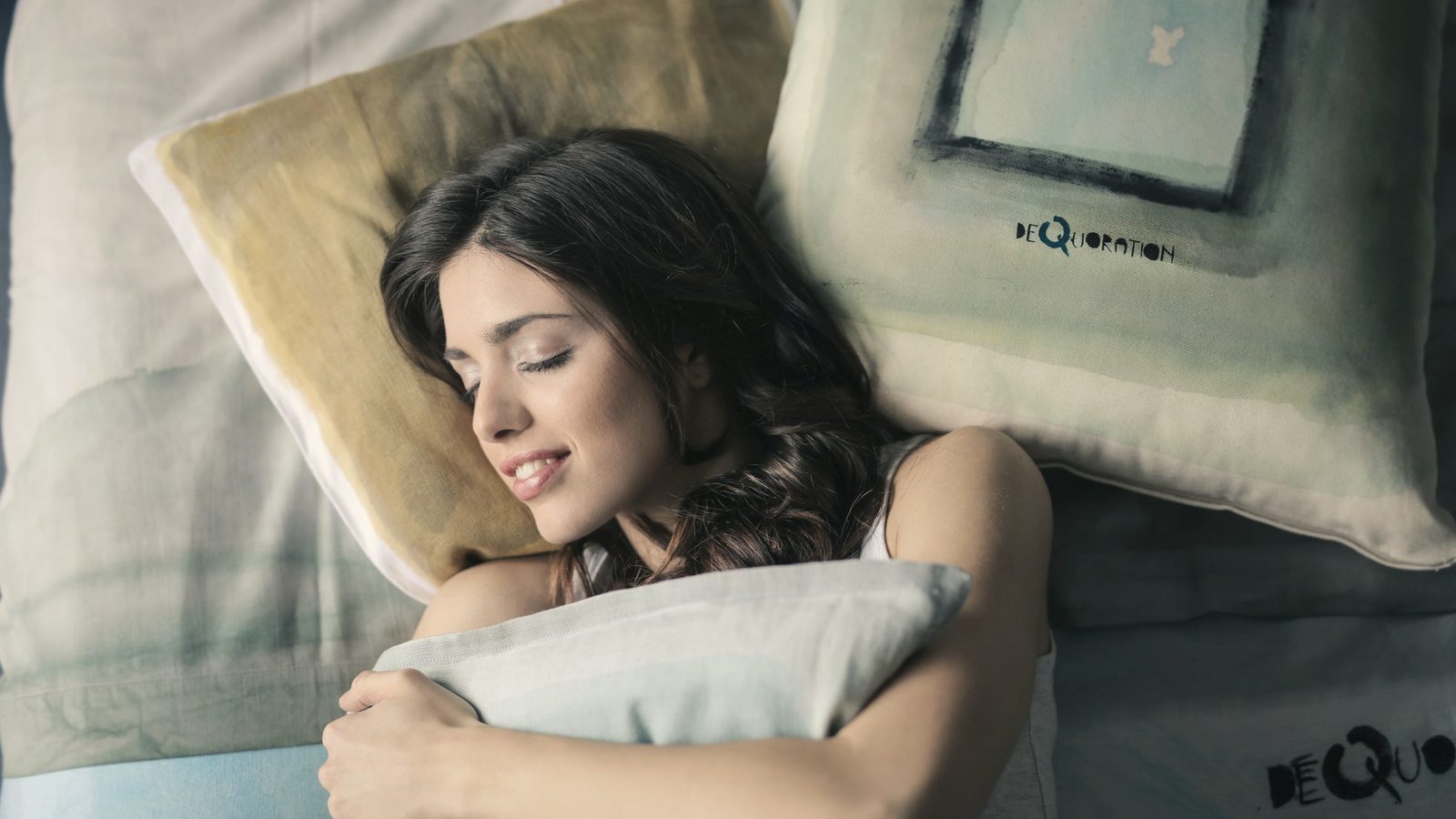 Woman sleeping peacefully on a grey bedspread