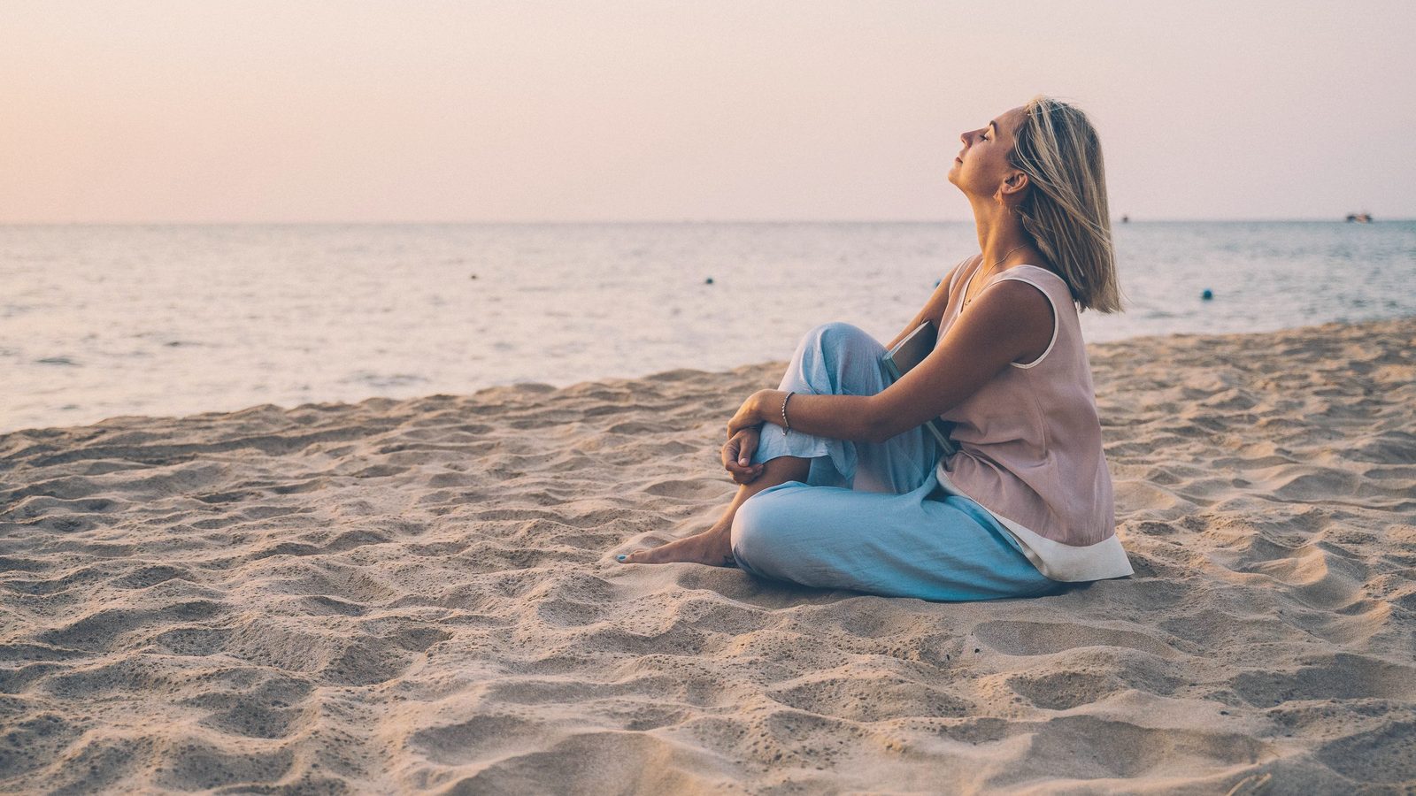 Woman sitting on the beach breathing in the sea air