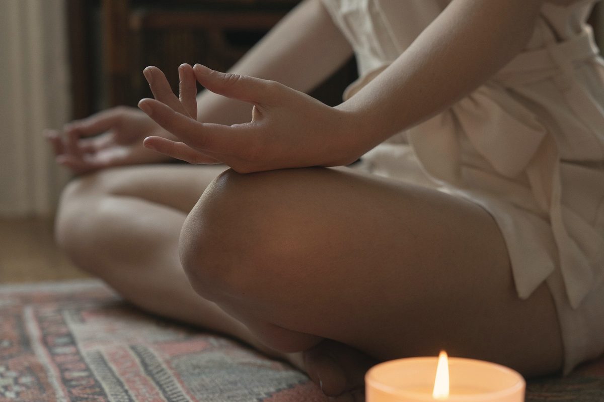 Woman meditating next to a lit candle