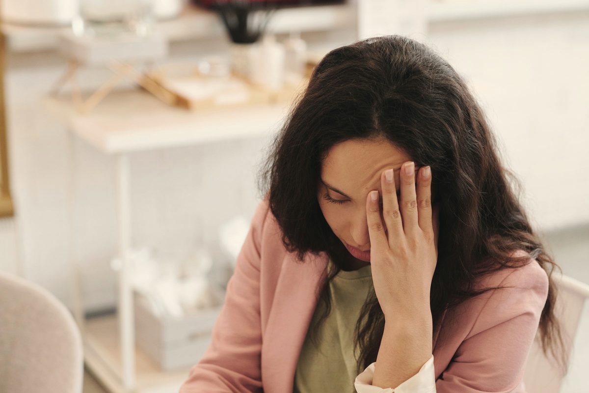 Woman holding her head while working on her laptop