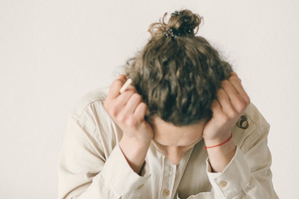 Exhausted man holding his head over his laptop