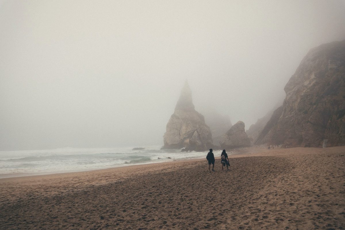 People walking along a misty beach