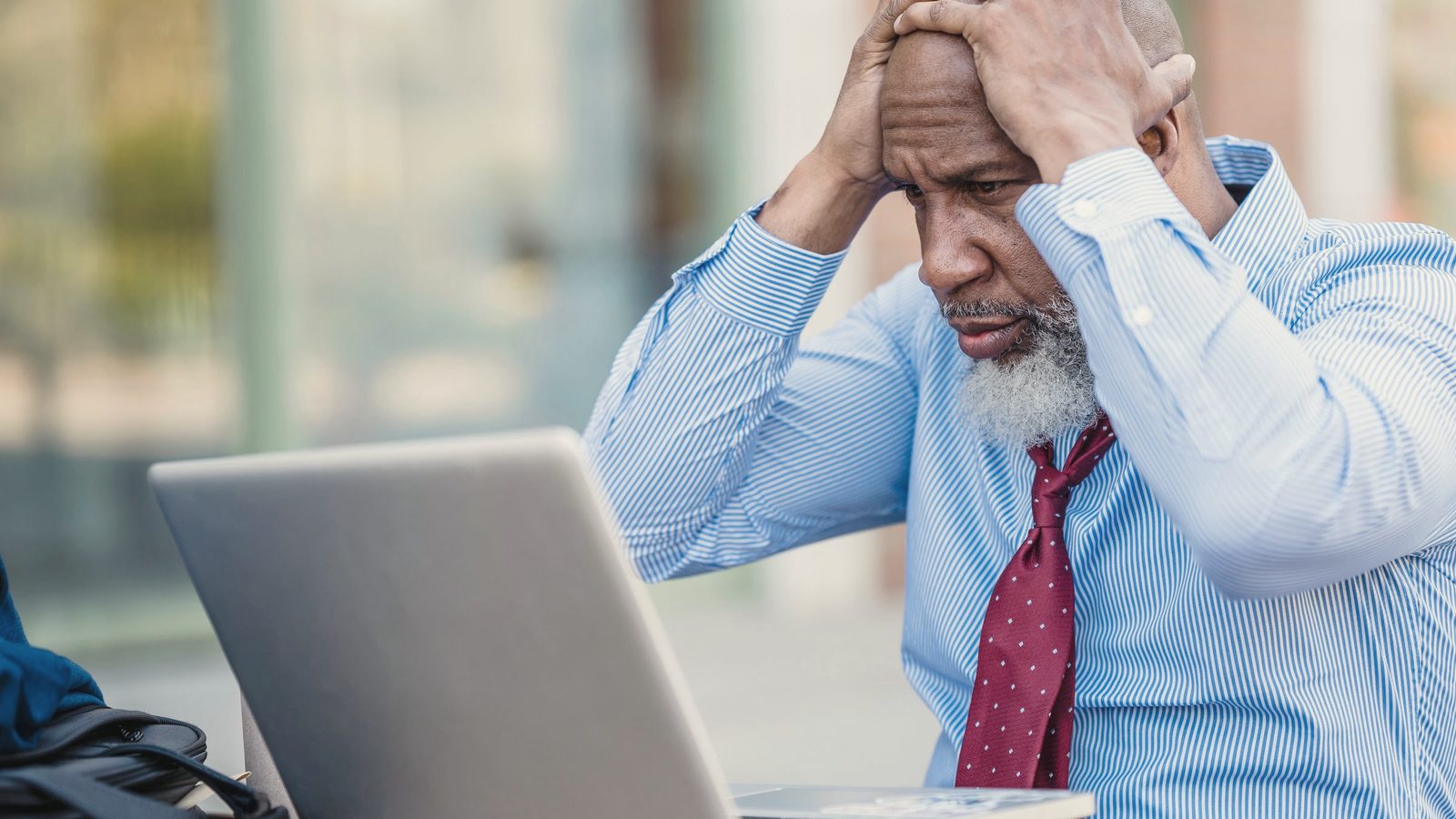 Stressed man holding his head while working on a laptop