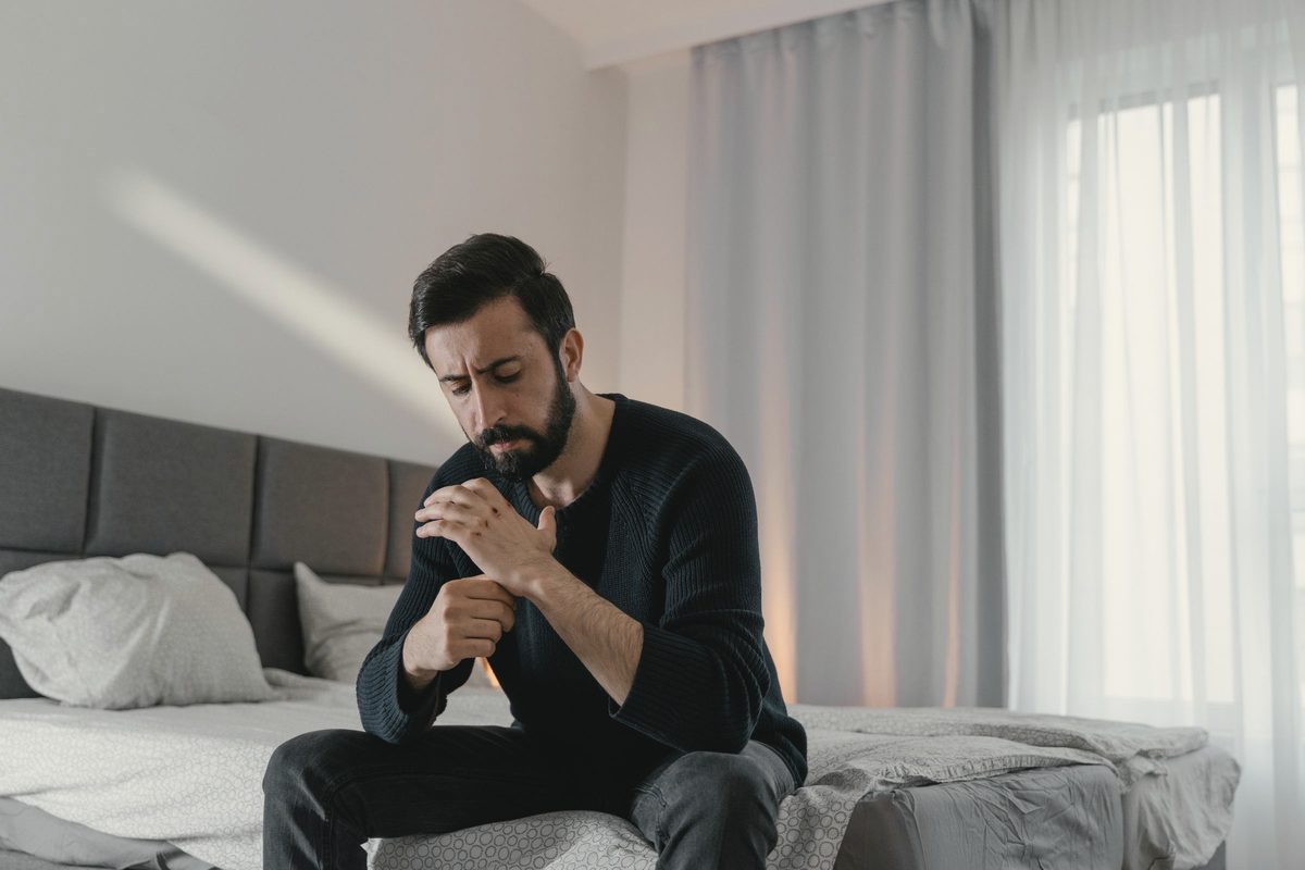 Man sitting on the edge of his bed looking worried