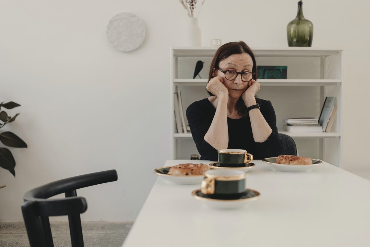 Older woman looking thoughtful at her kitchen table