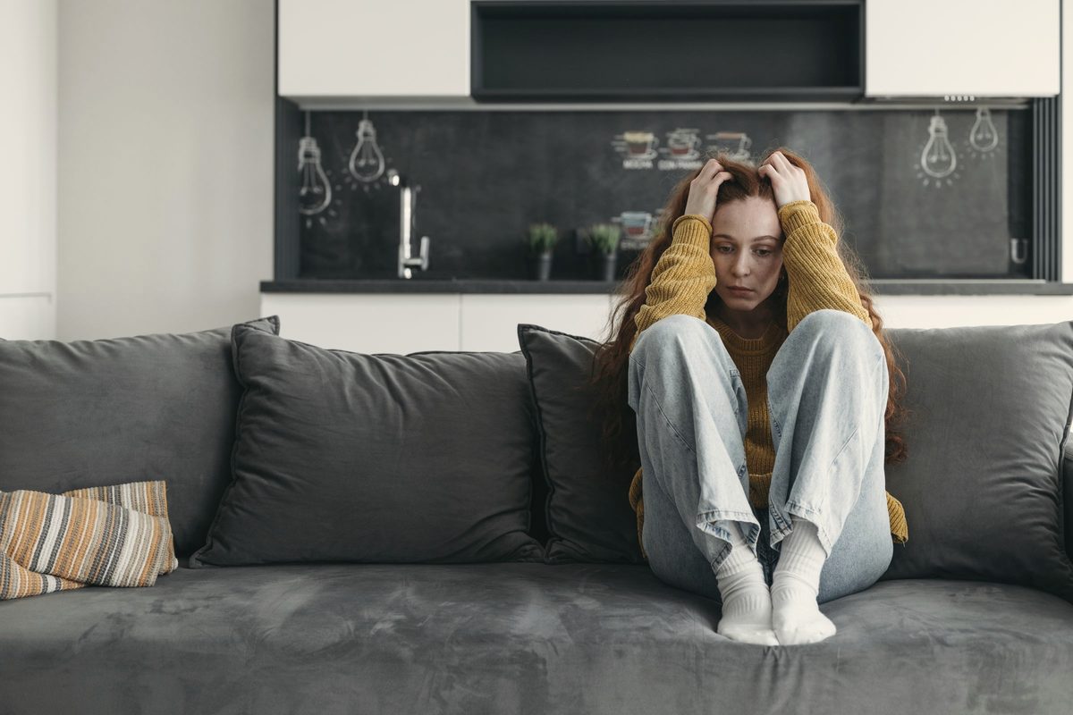 Anxious woman holding her head on the sofa