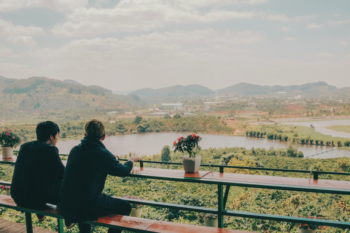 Two people sitting on chairs in front of a lake and mountains