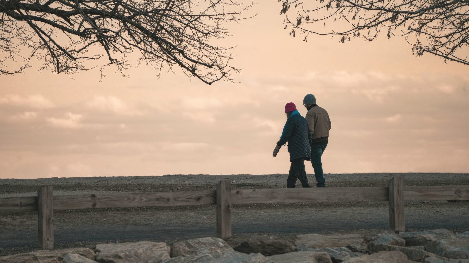 Elderly couple walking at sunset in autumn park