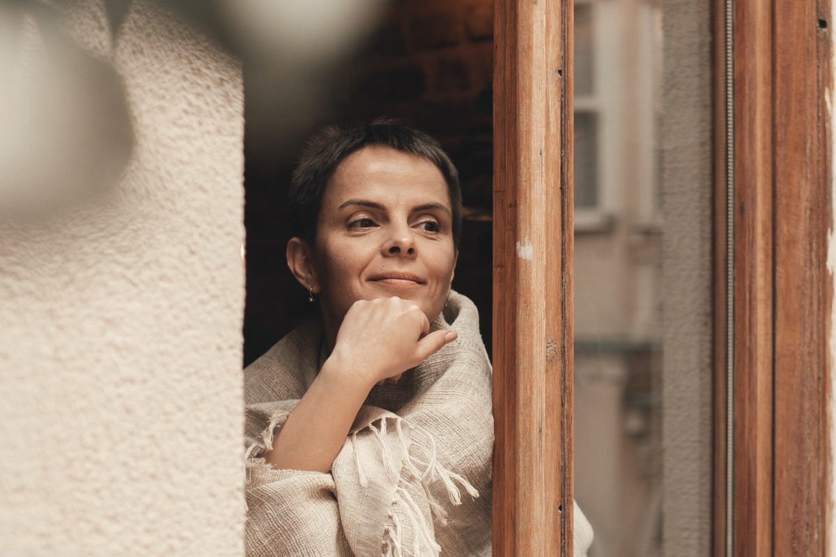 Smiling woman looking out of window at home