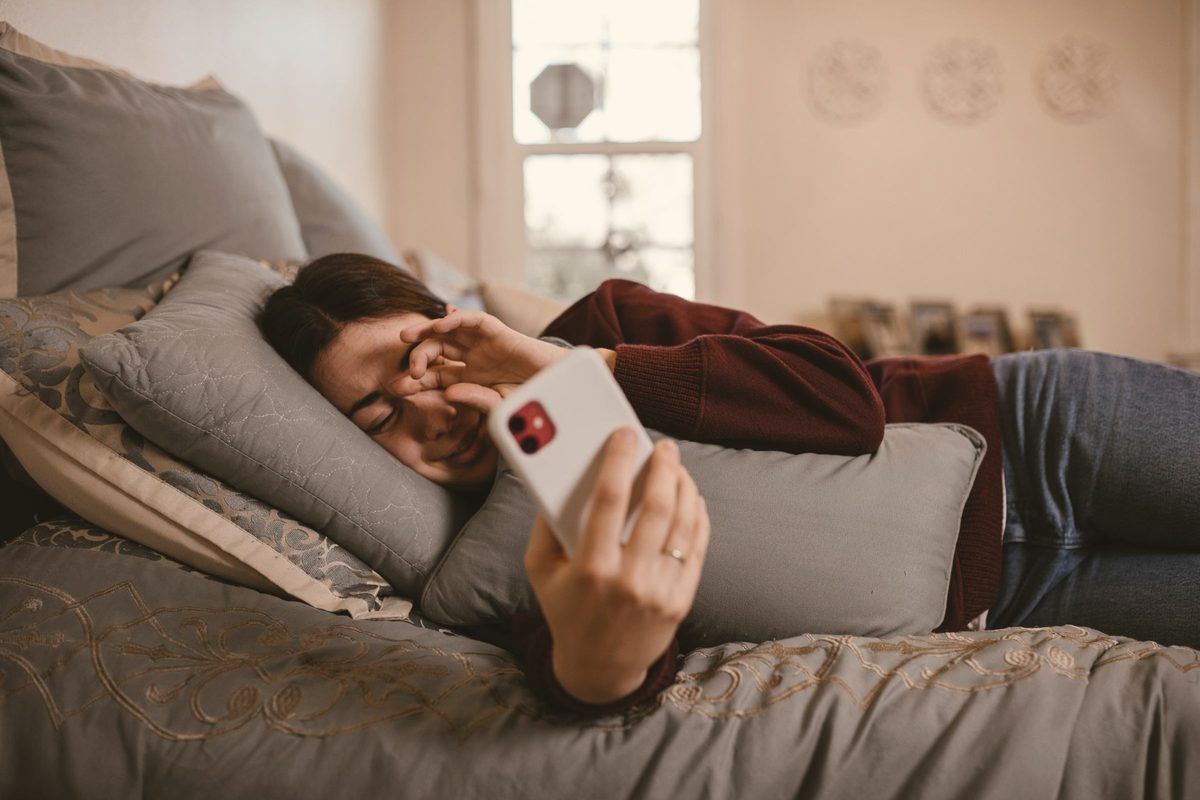 A woman using a smartphone on the bed