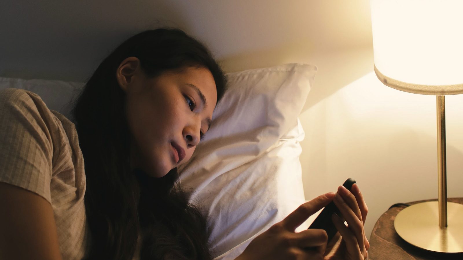 A woman lying on the bed while using her mobile phone
