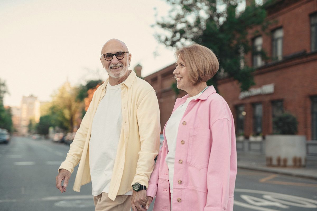 Happy elderly couple holding hands while walking on the street